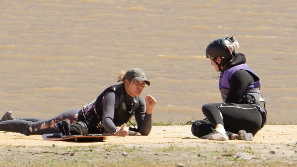 Clase teórica de kitesurf en la orilla: instructora explicando a la alumna en el Embalse Puclaro