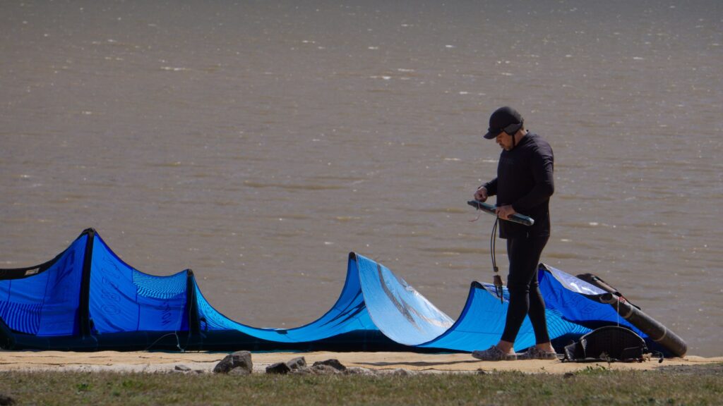 Kites azules inflados en la orilla del Embalse Puclaro mientras un rider prepara su equipo