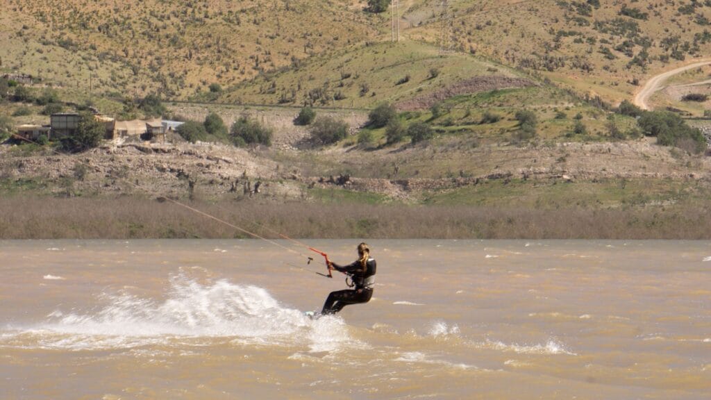 Rider de kitesurf navegando a toda velocidad y levantando agua en el Embalse Puclaro